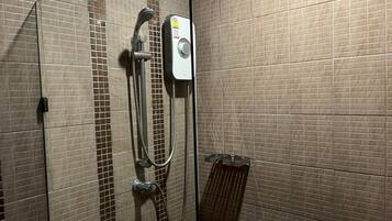 A shower with a handheld showerhead and a wall-mounted control panel.
