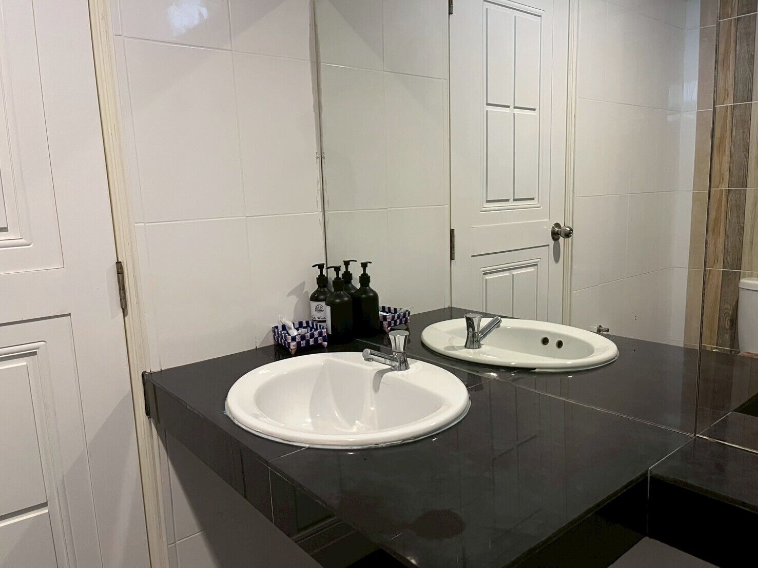 A bathroom with two sinks, a mirror, and toiletries on the counter.