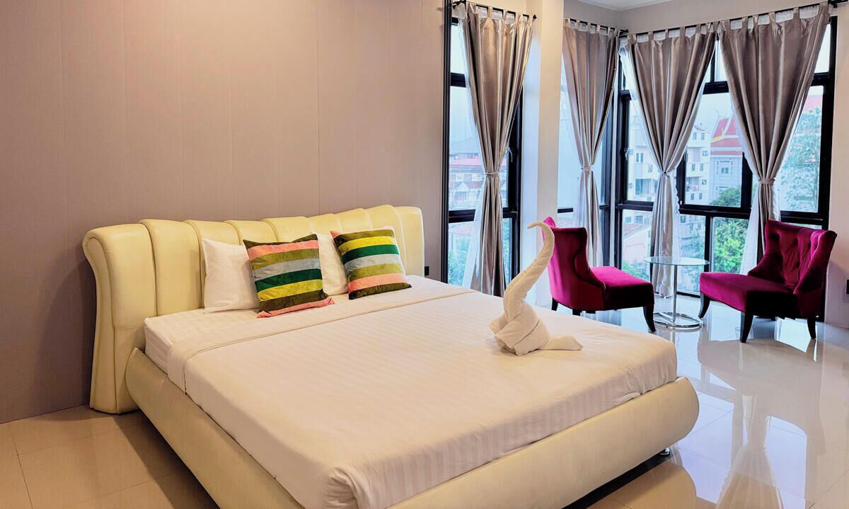 A hotel room with a large bed, two pillows, a white towel, and a chair.