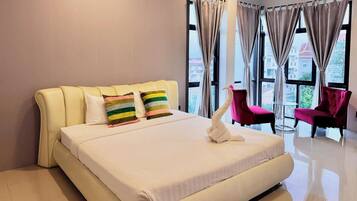 A hotel room with a large bed, two pillows, a white towel, and a chair.