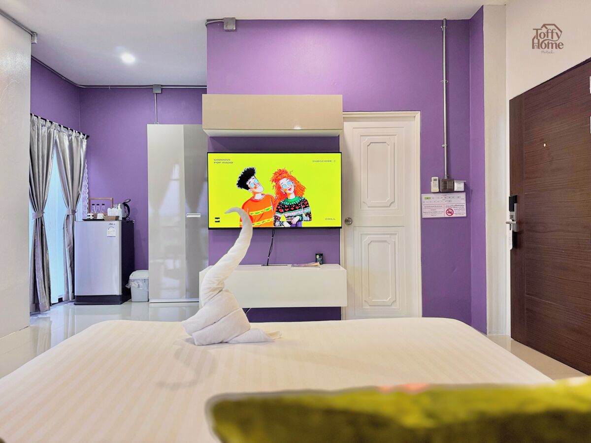 Una habitación de hotel con una cama, televisión, escritorio y armario.