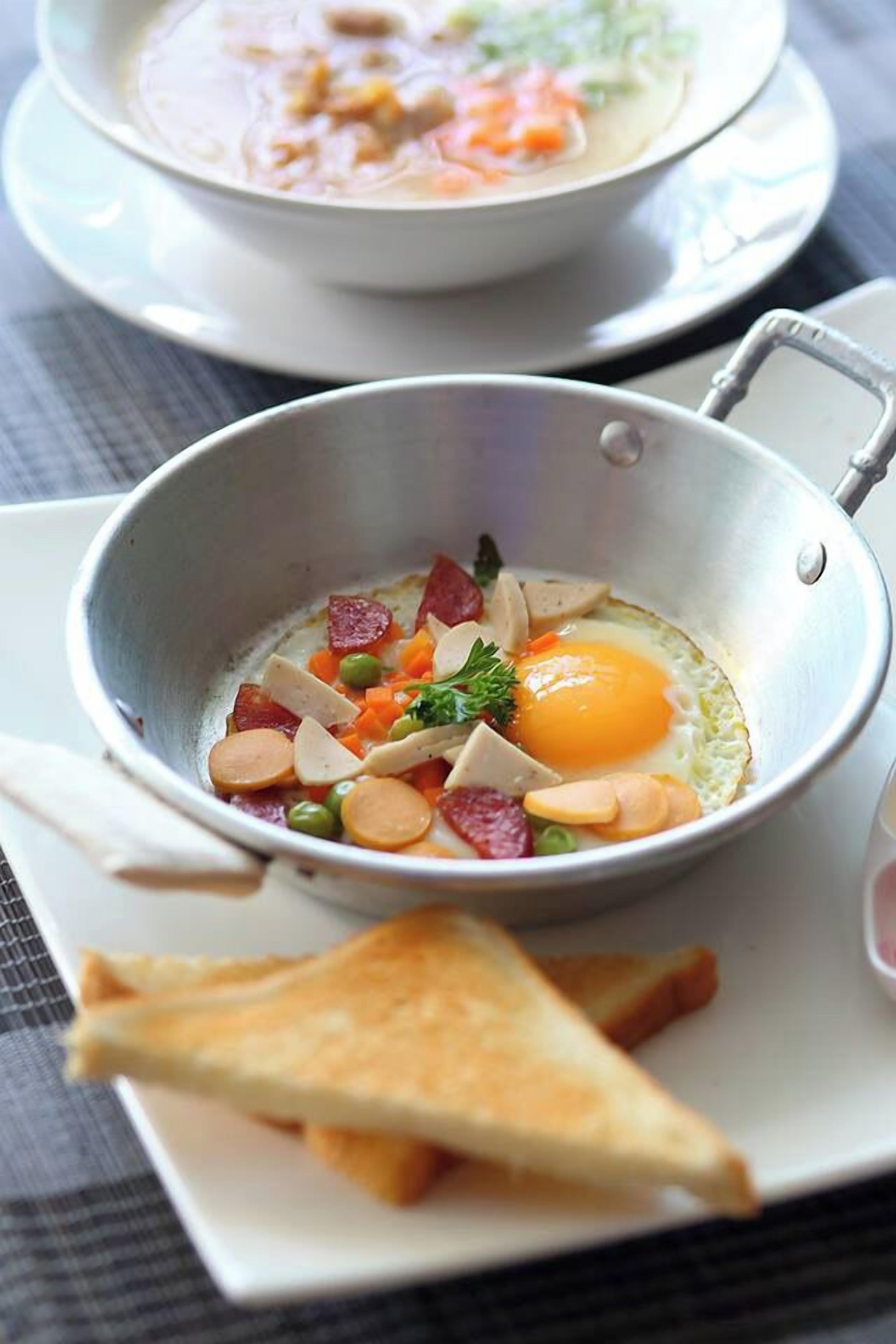 Un desayuno con un tazón de sopa y una sartén con huevos y vegetales.