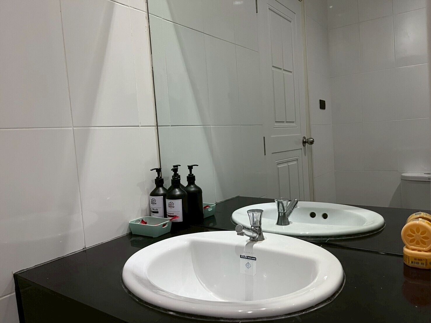 Un baño con dos lavamanos, un espejo y artículos de aseo en el mostrador.