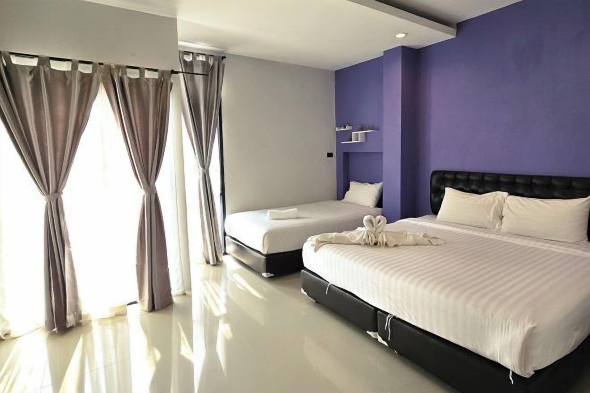 Habitació d'hotel moderna amb un llit gran, un altre més petit i una tocador amb calaixos.