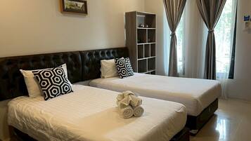 A hotel room with two beds, a bookshelf, and a framed picture on the wall.