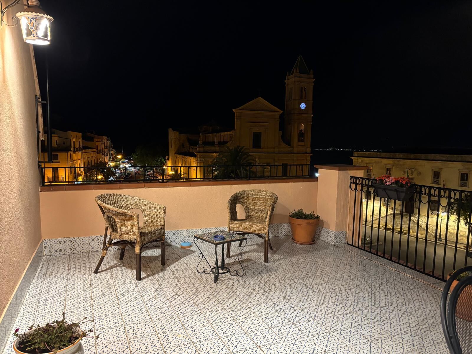 A balcony with two wicker chairs, a small table, and a potted plant.
