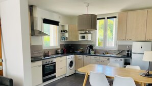 Une cuisine moderne avec un coin repas, comprenant une cuisinière, un four, un four à micro-ondes, un évier et une grande fenêtre.