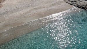 En strand med kristallklart, turkosfärgat vatten och en sandstrand.