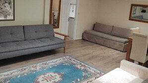A living room with a grey sofa, a patterned rug, and a small table. - Beautiful Apartment ac up to Six,12 min by Tube From Oxford Street,ac (London)