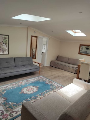 A living room with a grey sofa, a patterned rug, and a small table. - Beautiful Apartment ac up to Six,12 min by Tube From Oxford Street,ac (London)