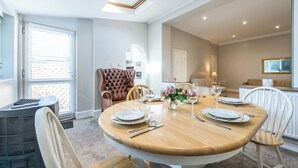A dining area with a round wooden table set for four, surrounded by white chairs. - Beautiful Apartment ac up to Six,12 min by Tube From Oxford Street,ac (London)
