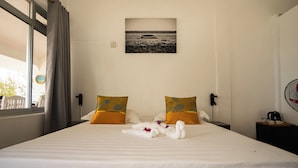 Hotelkamer met een groot bed, twee kussens, een aan de muur hangend schilderij, een nachtkastje en een raam met gordijnen.