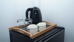 Een dienblad met een koffiezetapparaat, twee glazen recipiënten en twee koffiekopjes op een zwart apparaat.