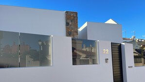 A modern building with a white facade, a stone chimney, and a black door.