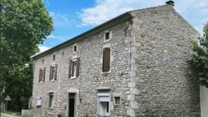 Un bâtiment en pierre de forme rectangulaire, doté de nombreuses fenêtres et d’une porte.