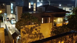 A residential area at night with modern houses, a street with parked cars, and streetlights.