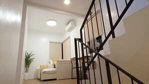 A modern interior with a staircase, a bed, a bedside table, and a potted plant.