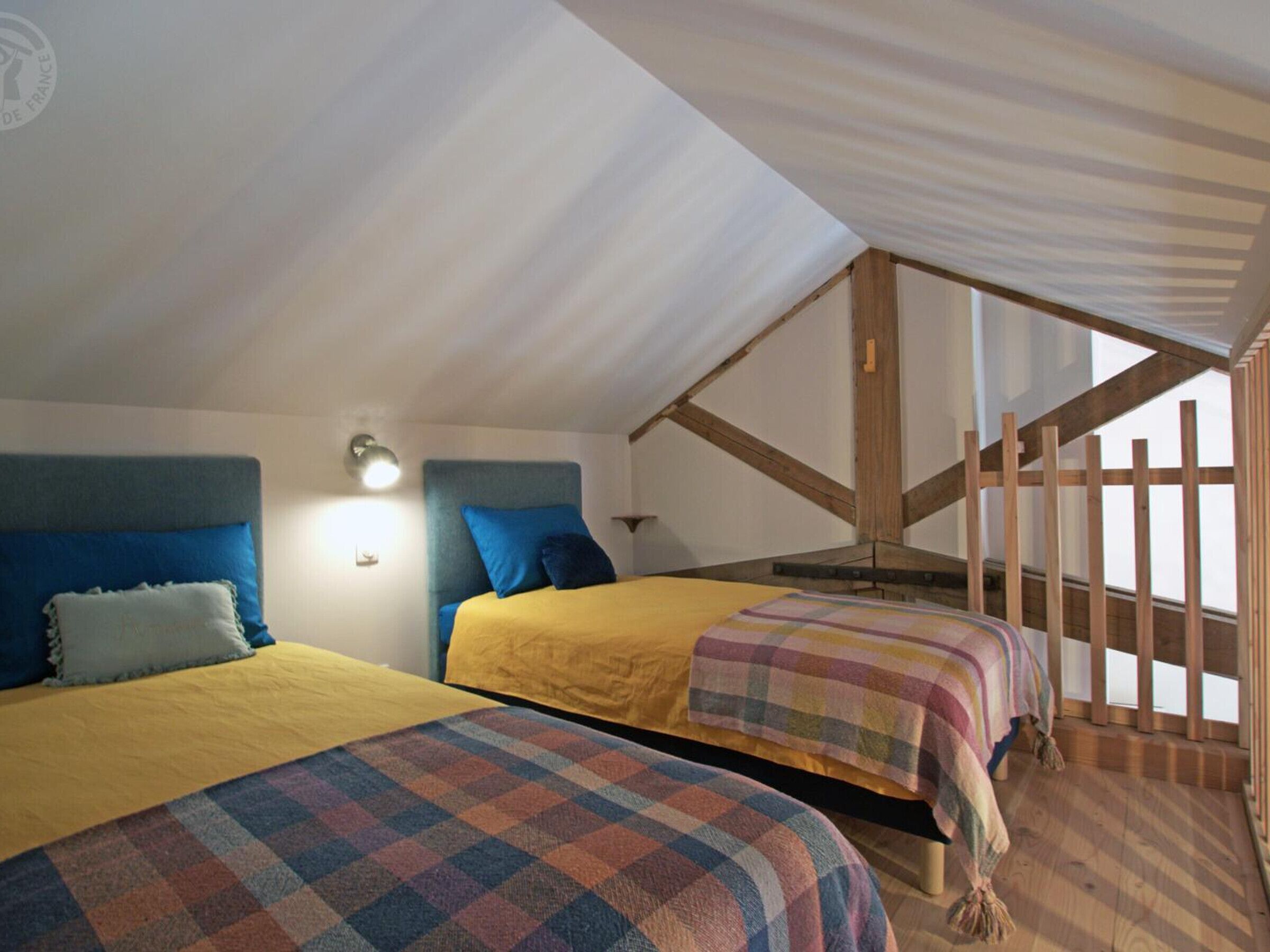 Ein Schlafzimmer mit zwei Betten, einem Holzbalkenbau und einem Fenster, das natürliches Licht hereinlässt.