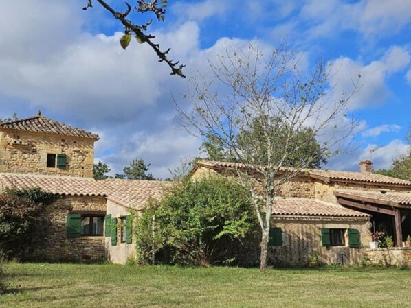 A traditional stone building with a tiled roof, green shutters, and a small tower-like structure. - Cottage for 8 with Fireplace and SPA in Biron (Biron)