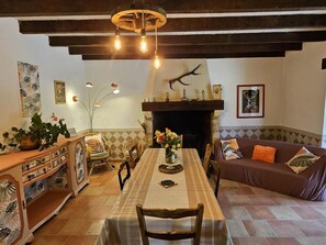 A cozy living room with a fireplace, a dining table, and a sofa. - Cottage for 8 with Fireplace and SPA in Biron (Biron)