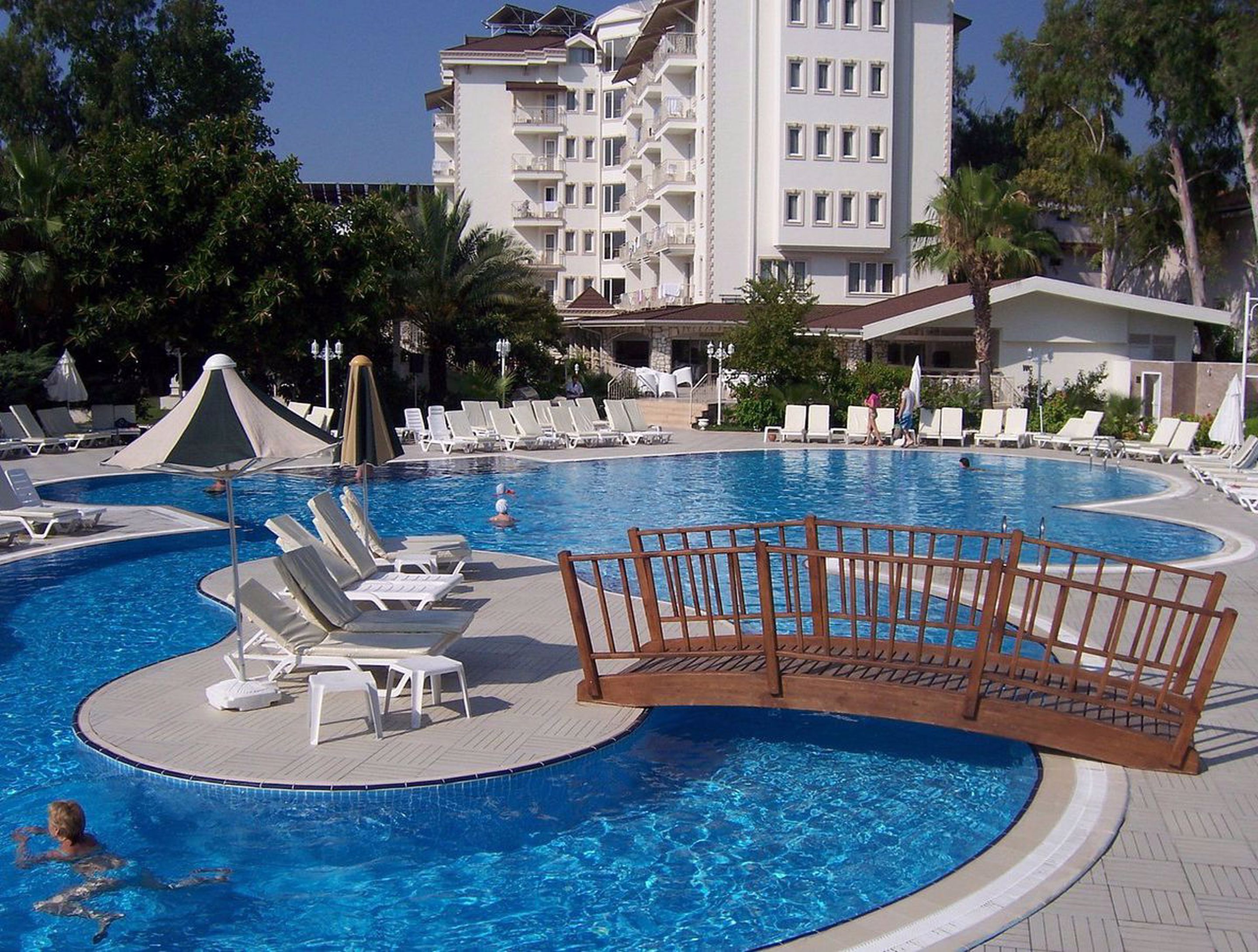 Una piscina con sillas de descanso y una terraza de madera.