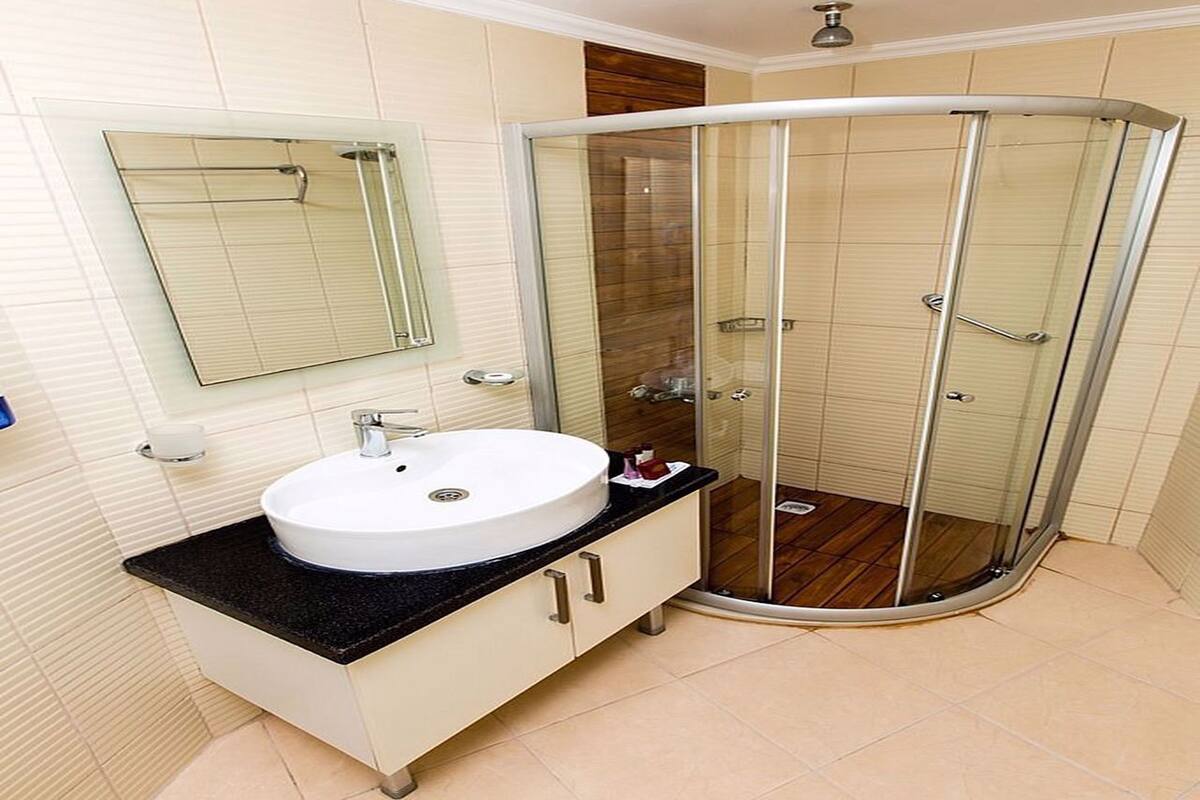 A modern bathroom with a white sink, a mirror, and a glass shower enclosure.