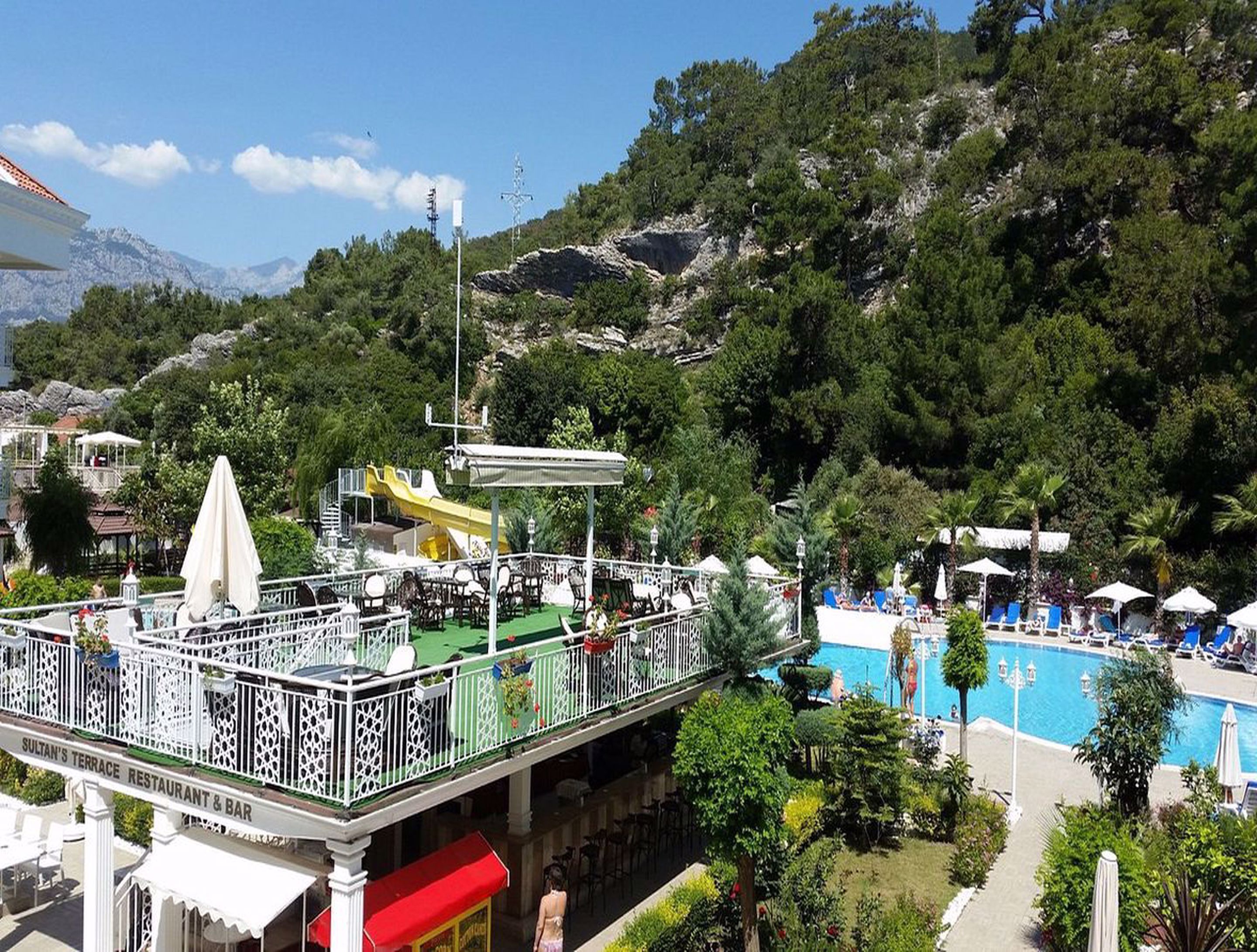 Ristorante con terrazza e posti a sedere all'aperto, affacciato su una piscina e con le montagne sullo sfondo.