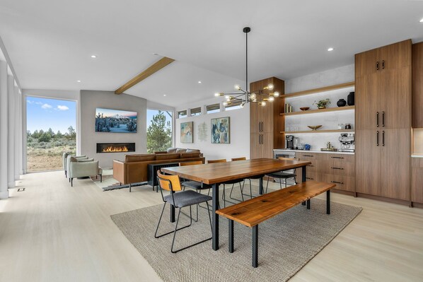 Une cuisine moderne avec des meubles en bois, un coin repas doté d’une grande table et de bancs, et une cheminée.