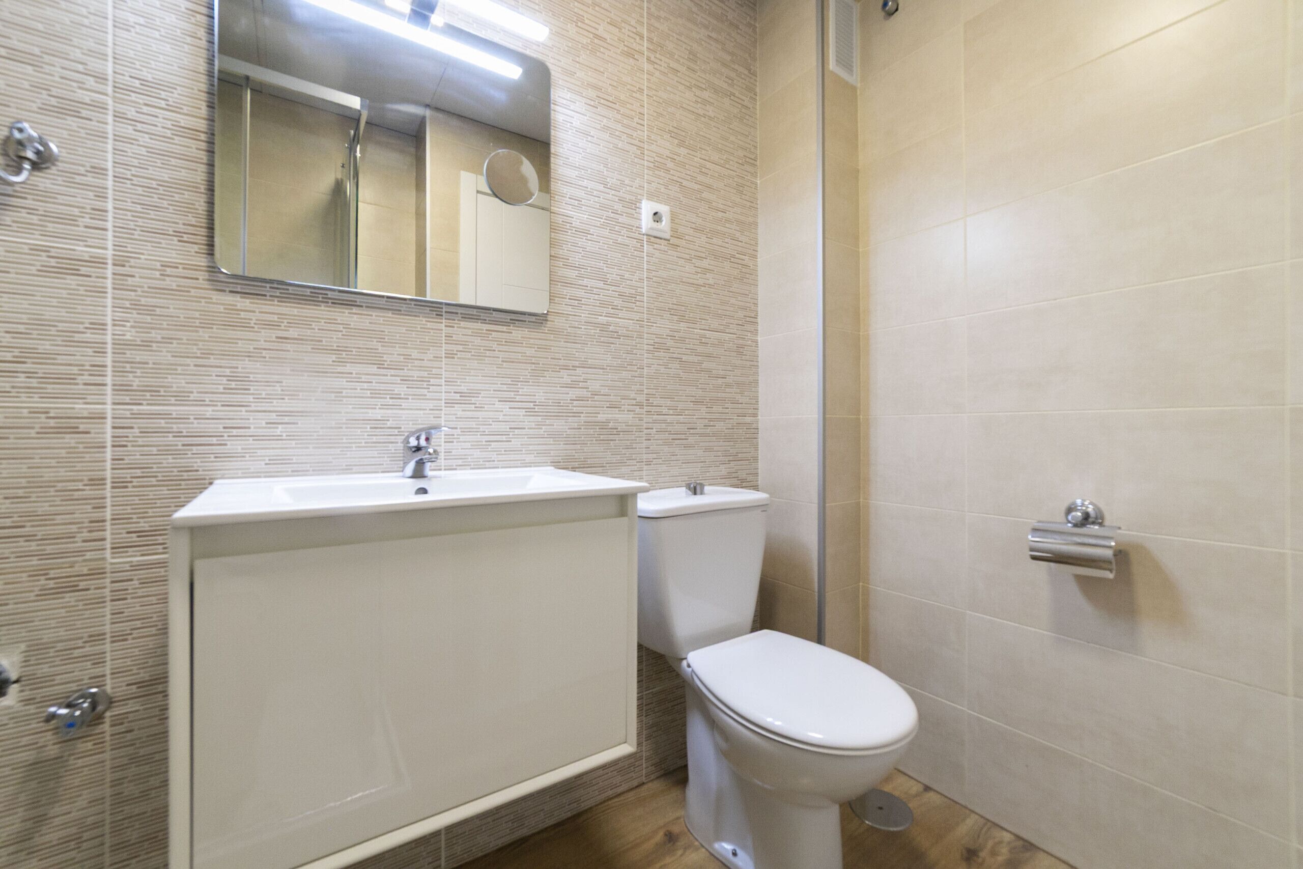 A bathroom with a sink, toilet, and mirror.