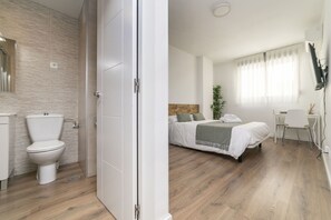 A modern bedroom with a bed, bedside table, and a desk.