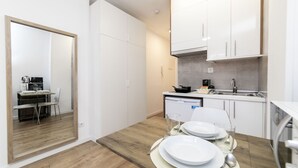 Una cocina moderna con armarios blancos, una mesa de comedor de madera dispuesta para dos personas, y vista hacia el área de comedor contigua.