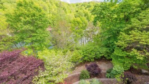 A lush garden with a variety of trees and shrubs, a small pond, and a wooden deck. - Private lakefront home with dock, forest views, balconies, game room, and cozy indoor charm (Dublin)