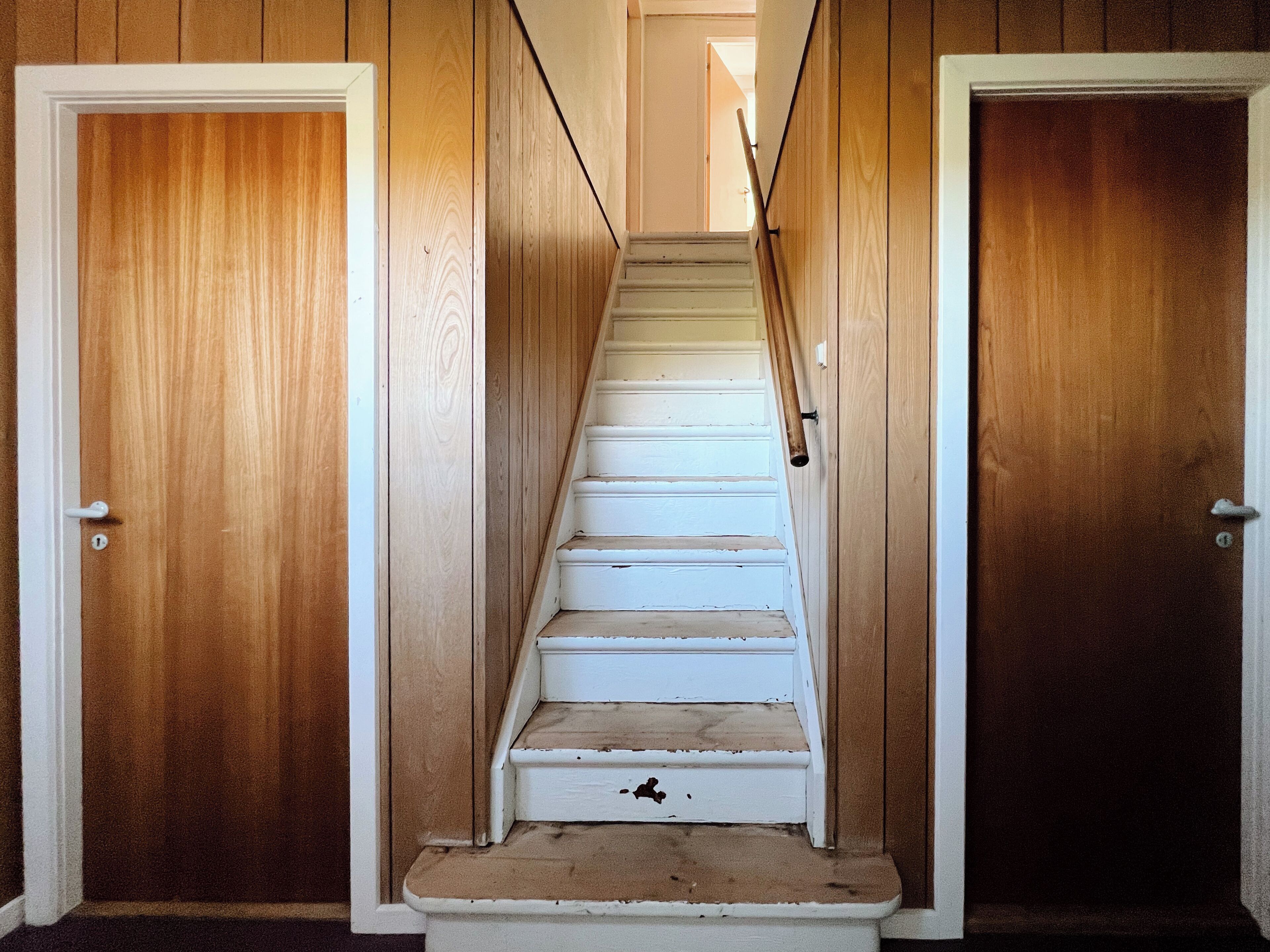 Un escalier aux marches blanches menant à une porte située en haut.