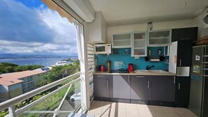 Una cocina con vista al mar, un balcón y un comedor.