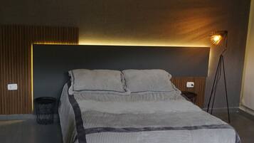 Un dormitorio moderno con una cama grande, una lámpara colgante geométrica y una lámpara de pie.