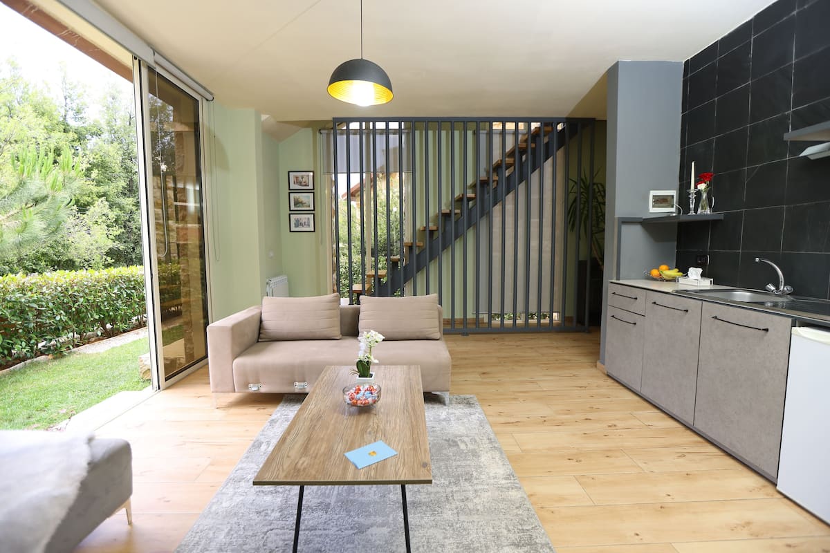 A modern kitchen with grey cabinets, a wooden dining table, and a staircase leading to an upper level.