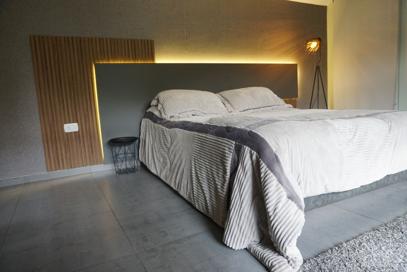A modern bedroom with a bed, a bedside lamp, and a small round table.