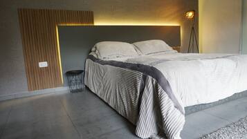 A modern bedroom with a bed, a bedside lamp, and a small round table.