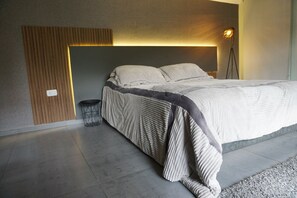 A modern bedroom with a bed, a bedside lamp, and a small round table.
