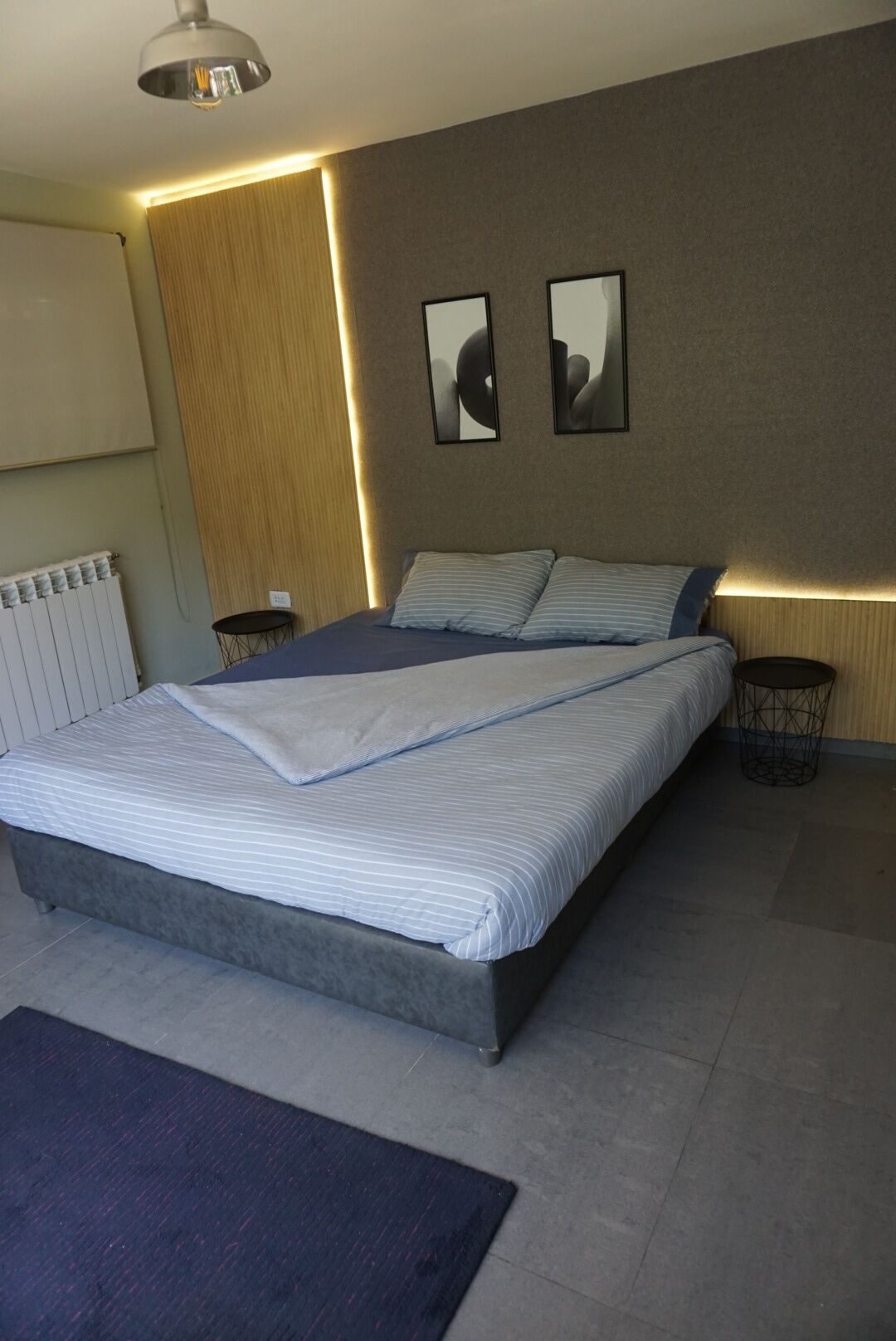 A modern bedroom with a large bed, bedside tables, and wall-mounted artwork.