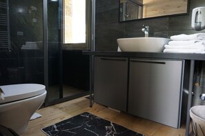 A modern bathroom with a toilet, a sink, and a shower.