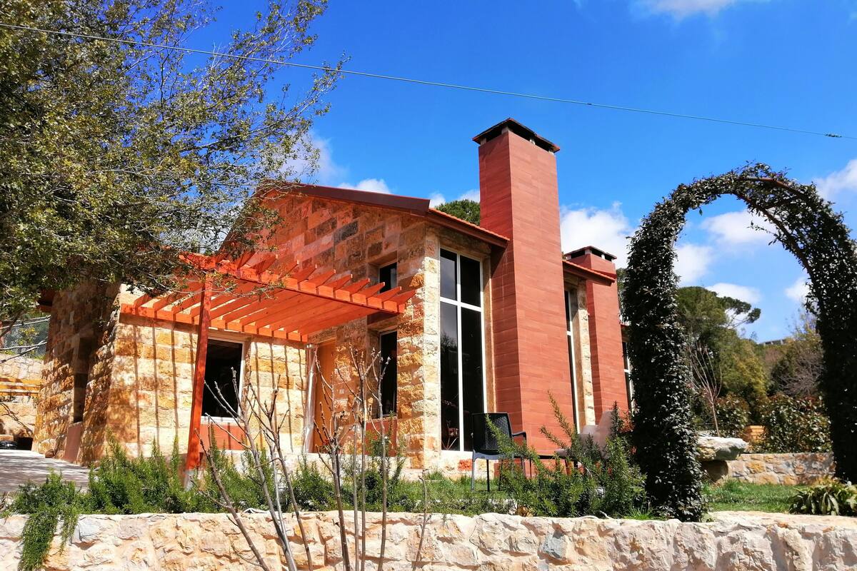 A stone building with a red roof and a chimney.