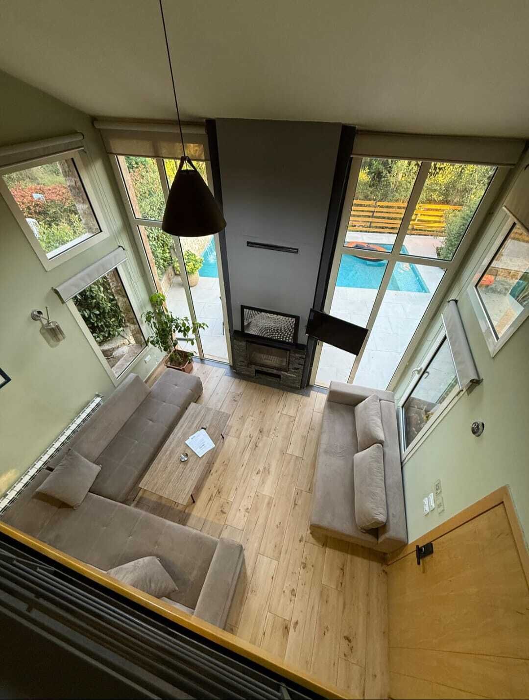 A modern living room with a fireplace, two sofas, and a view of a swimming pool.