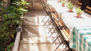 A rustic outdoor dining area with a long table, chairs, and potted plants. - A Cozy Place Penang (George Town)