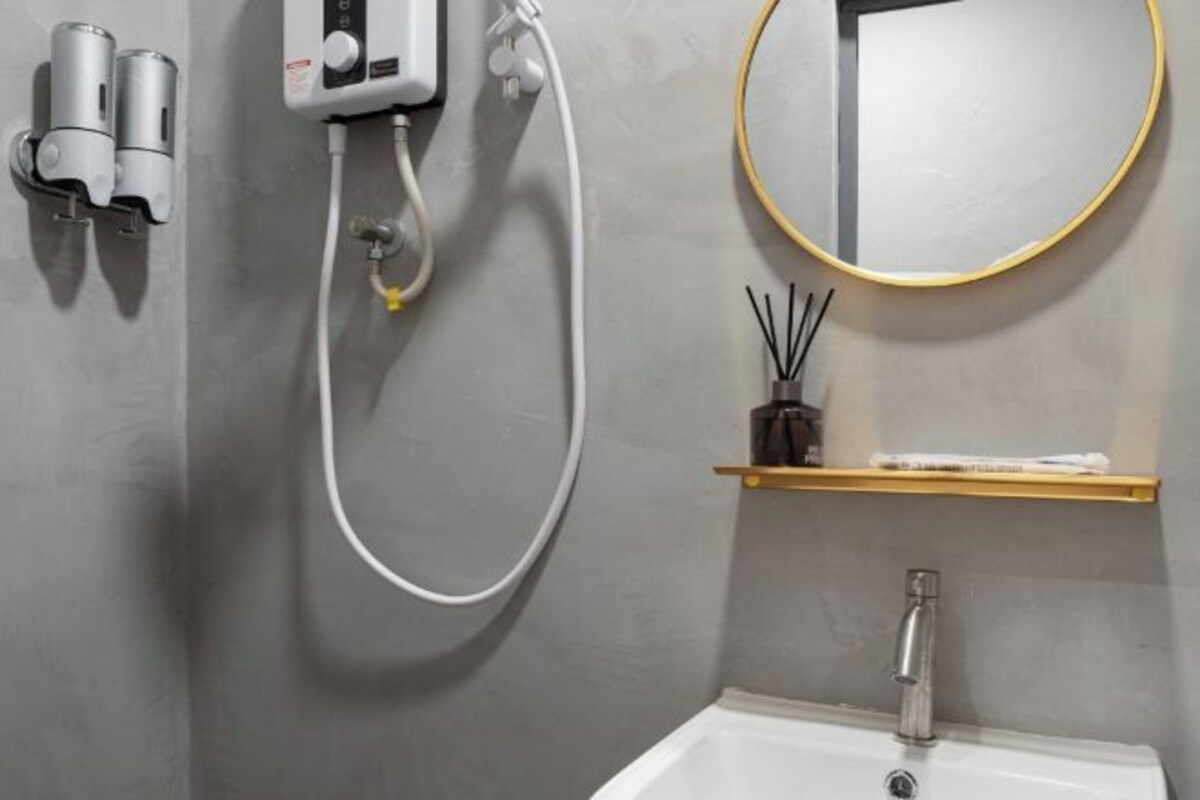 A bathroom with a shower, a sink, a mirror, and a shelf with toiletries.