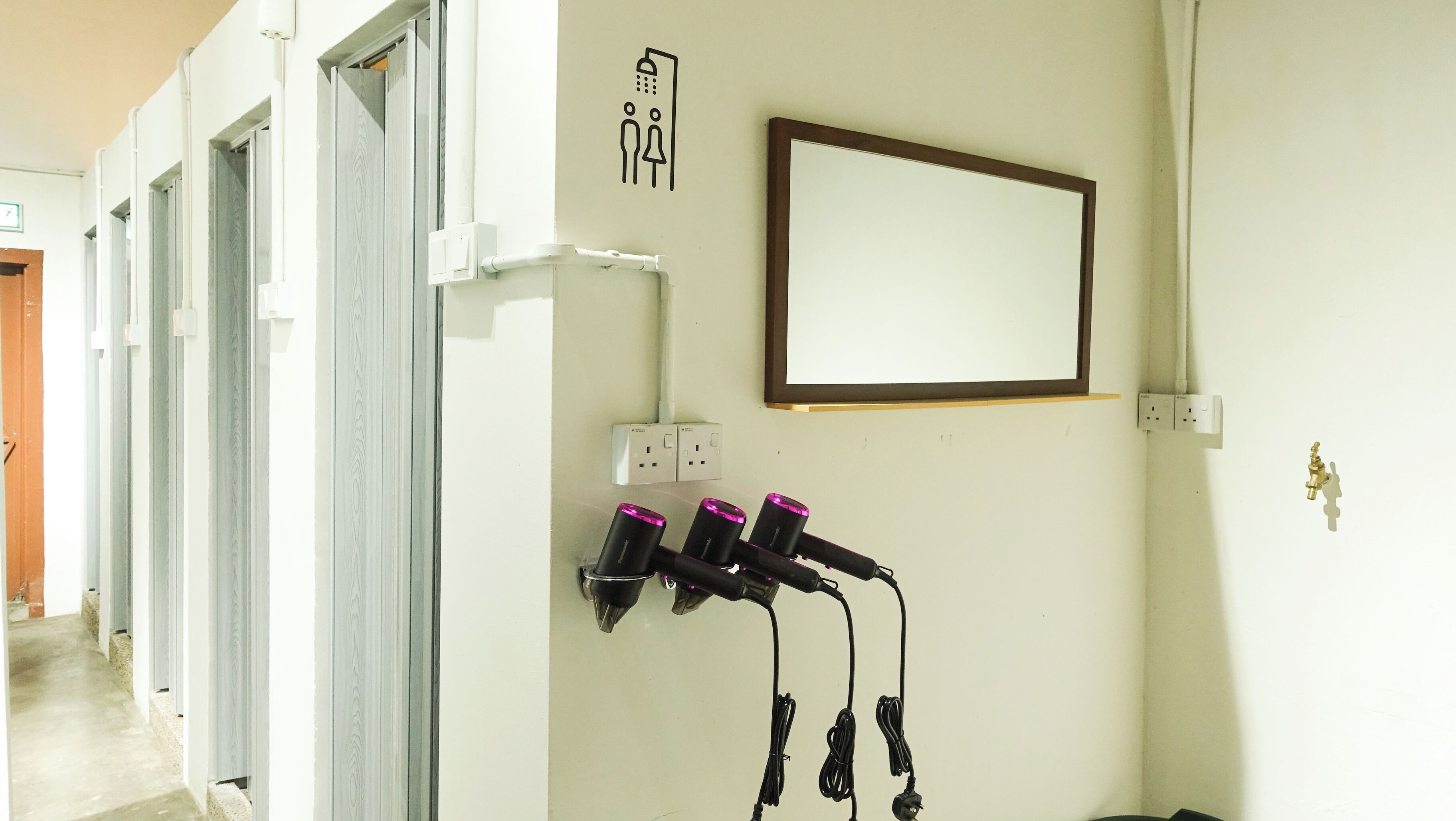 Habitación de hotel con un espejo grande, un enchufe en la pared y un perchero con varias toallas.