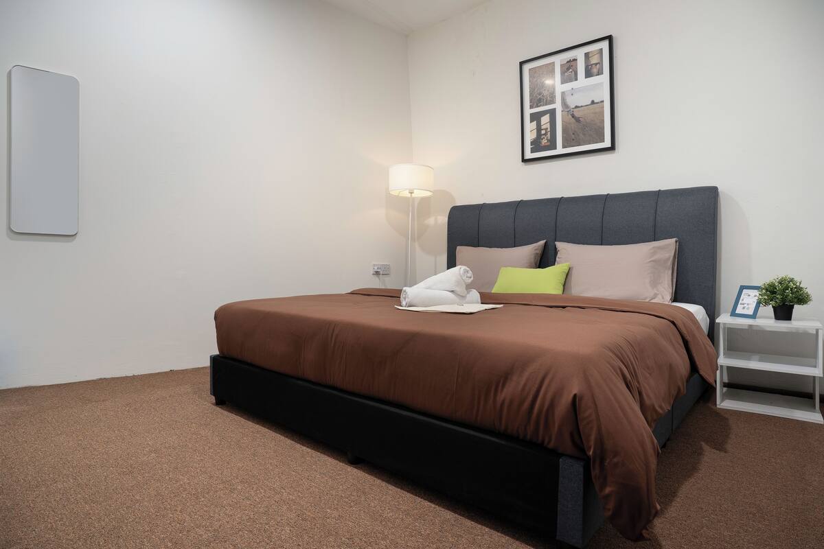 A modern bedroom with a large bed, a bedside table with a lamp, and a framed picture on the wall.