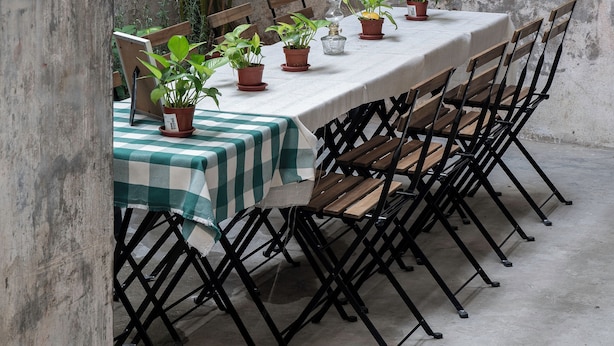 A rustic outdoor dining area with a table set for six, surrounded by chairs, and potted plants. - A Cozy Place Penang (George Town)