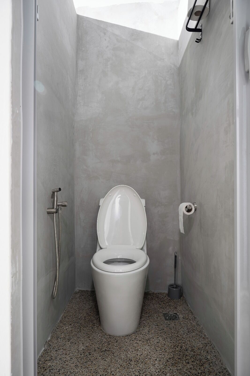 A small, modern bathroom with a white toilet, a shower, and a toilet paper holder.
