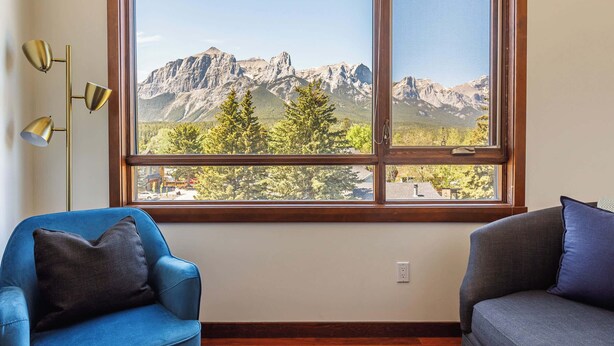 A room with a large window offering a mountain view, two sofas, and a floor lamp.
